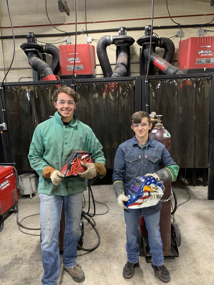 Landyn and Noah holding their welding helmets