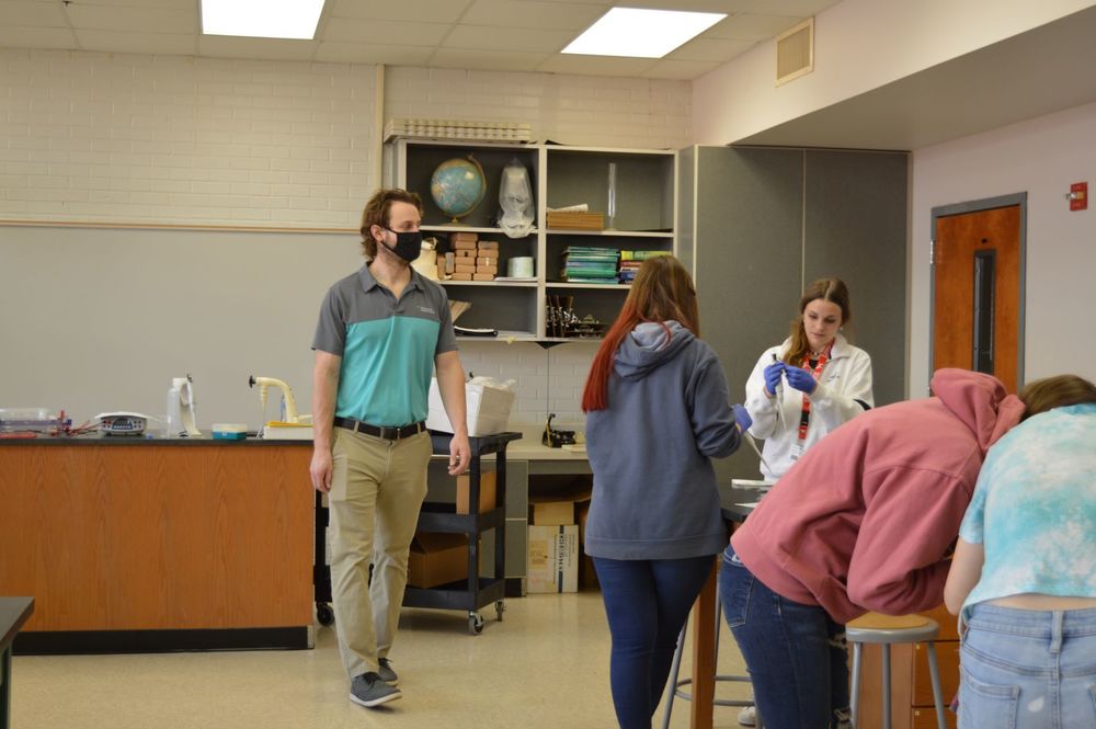 The instructor from Greenwood Genetic Center observes the students as they work on their crime lab. 