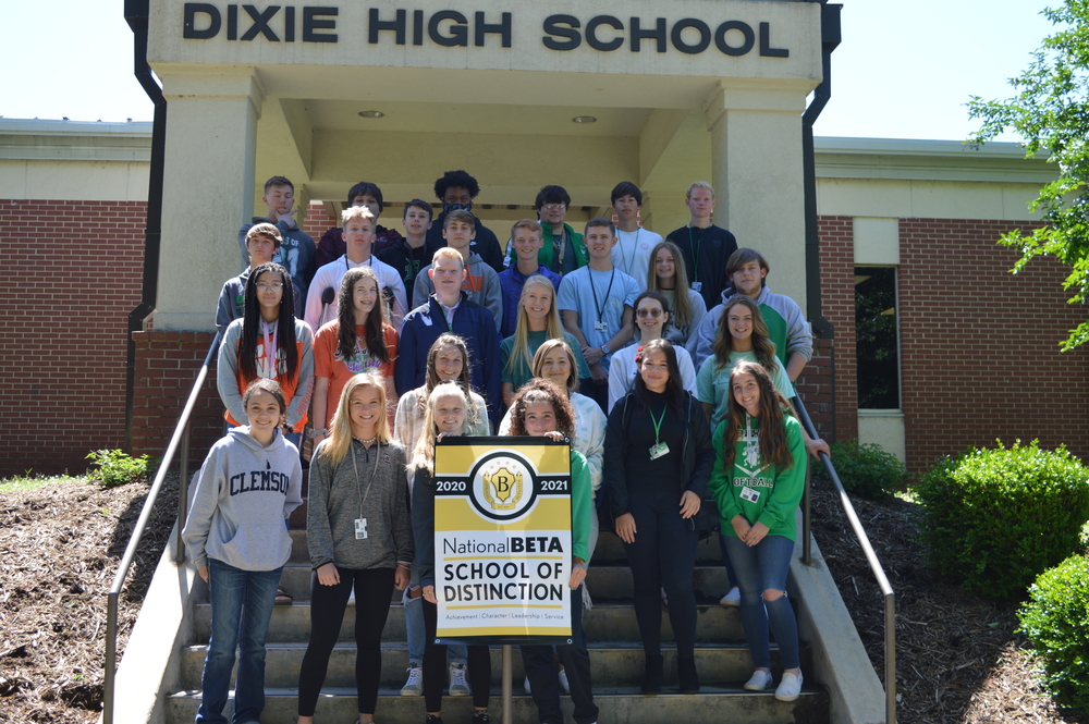Students standing on front steps holding the National Beta School of Distinction sign.